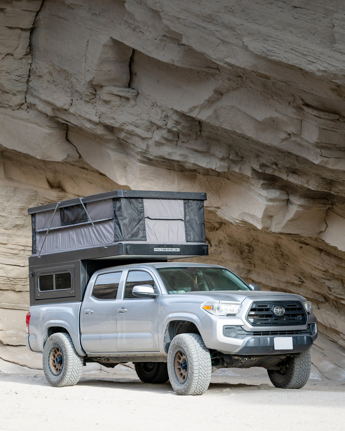The Bruin hardwall pop-up truck camper on a Toyota Tacoma against rock formations
