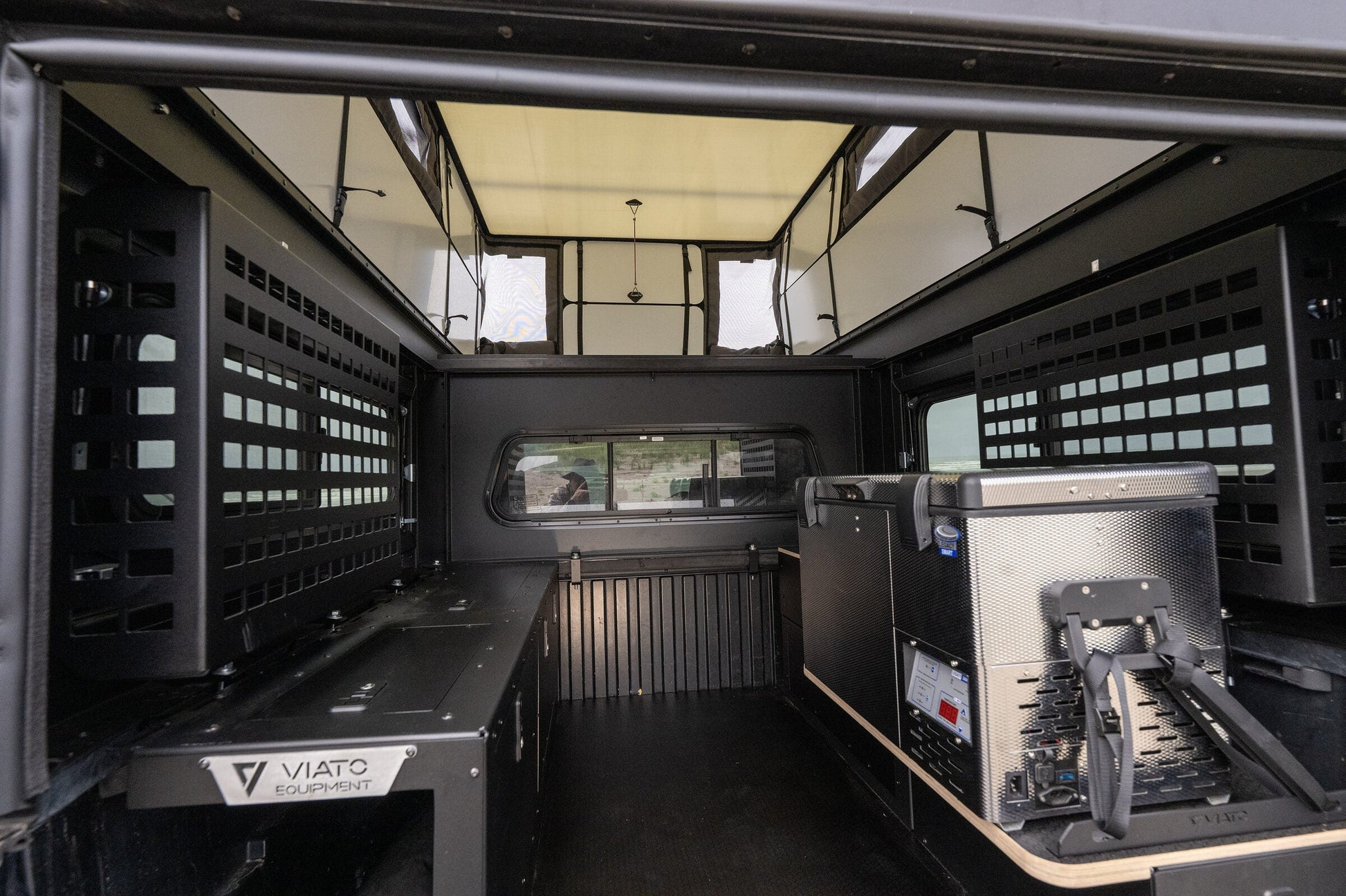 Inside the Oru Bruin truck camper, looking down the full length past the galley counter and gear panels to the open floor