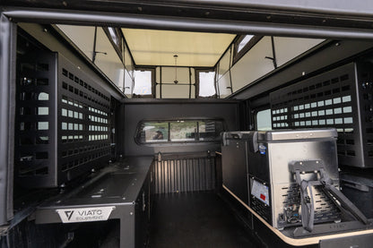 Inside the Oru Bruin truck camper, looking down the full length past the galley counter and gear panels to the open floor