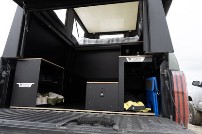 Oru Triton camper interior from the tailgate with the galley cabinets open and gear stowed on the bed floor