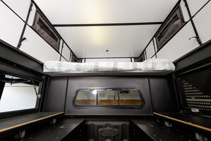 Inside the Oru Bruin XL looking forward, the bed platform stowed high and the full length of the floor left clear