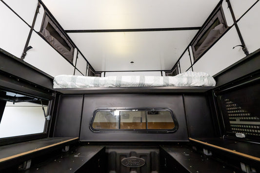 Inside the Oru Bruin XL looking forward, the bed platform stowed high and the full length of the floor left clear